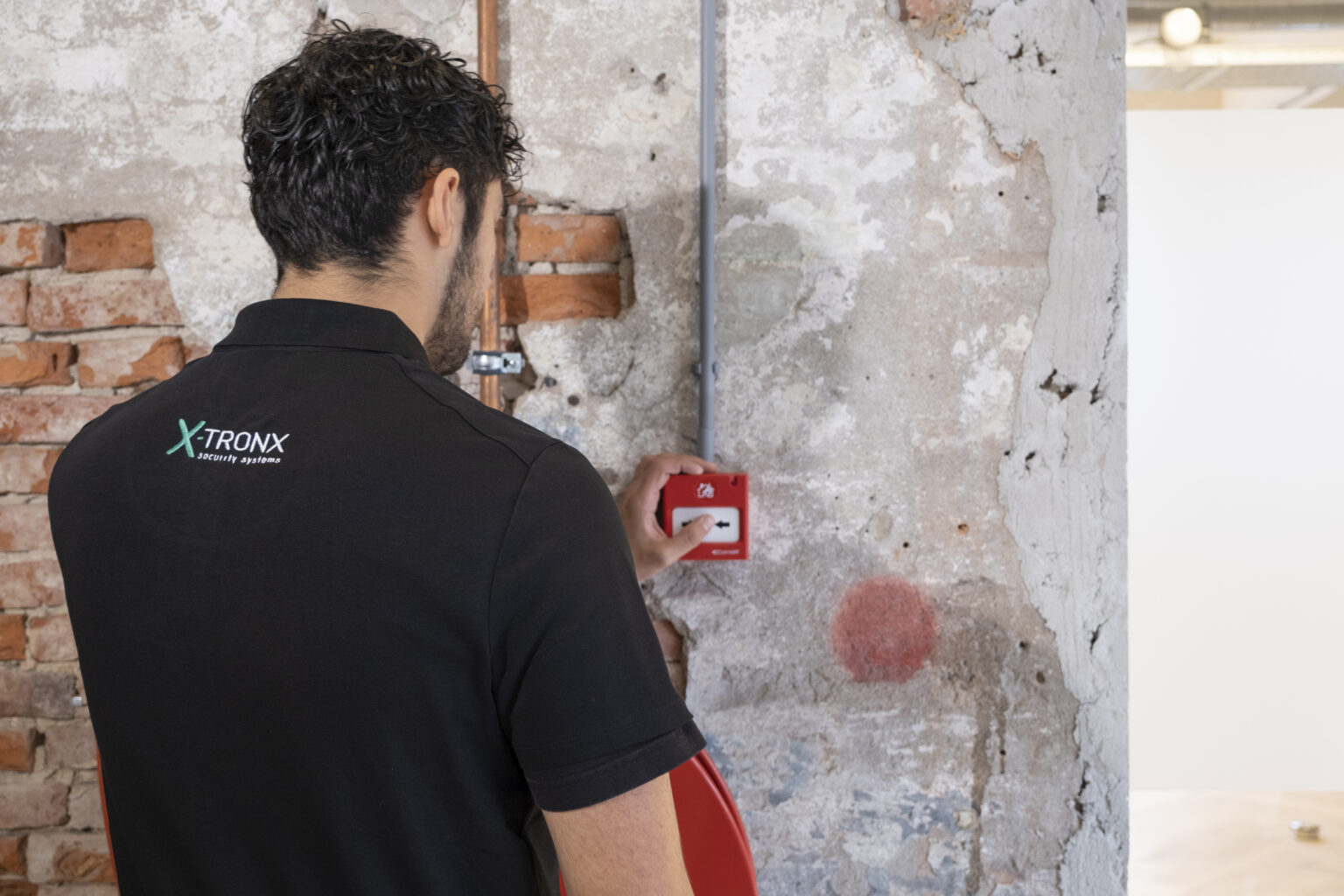 X-Tronx monteur installeert een handbrandmelder voor professionele brandbeveiliging